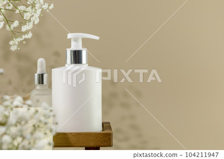 Eco friendly spa relax composition with mockup of beauty product in dispenser bottle on wooden podium with white flowers. Wellness and skin care treatment. Concept of me time and self care. Copy space Eco friendly spa relax composition with mockup of beauty product in dispenser bottle on wooden podium with white flowers. Wellness and skin care treatment. Concept of me time and self care. Copy space 104211947