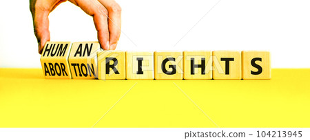 Abortion rights symbol. Concept words Abortion rights are human rights on wooden cubes. Businessman hand. Beautiful yellow table white background. Business medical abortion rights concept. Copy space. Abortion rights symbol. Concept words Abortion rights are human rights on wooden cubes. Businessman hand. Beautiful yellow table white background. Business medical abortion rights concept. Copy space. 104213945