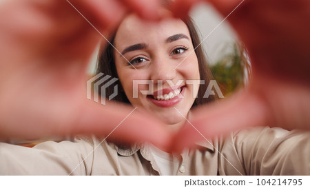 Happy young woman girl makes symbol of love showing heart sign to camera express romantic feelings Happy young woman girl makes symbol of love showing heart sign to camera express romantic feelings 104214795