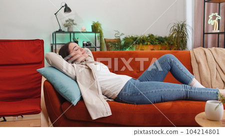 Tired lazy woman enjoy relaxing on home sofa resting napping after hard working day, closed her eyes Tired lazy woman enjoy relaxing on home sofa resting napping after hard working day, closed her eyes 104214801