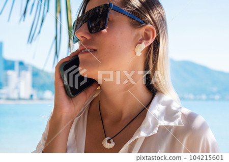 Beautiful woman wearing sunglasses talking on smartphone. Summery female portrait. Beautiful woman wearing sunglasses talking on smartphone. Summery female portrait. 104215601