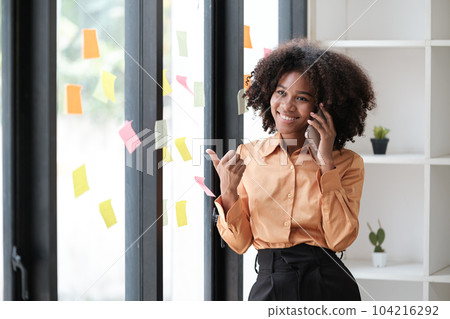 African American female employee write down on colorful sticky notes manage list, concentrated biracial woman work on startup brainstorm collaborate plan on stickers on glass wall African American female employee write down on colorful sticky notes manage list, concentrated biracial woman work on startup brainstorm collaborate plan on stickers on glass wall 104216292