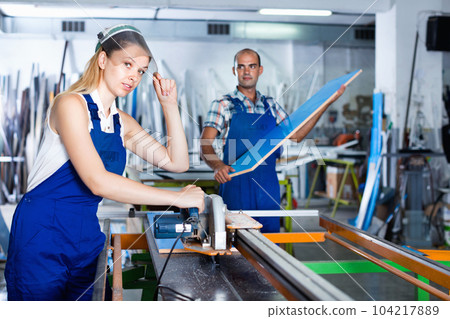 Female worker in protective face shield, standing near circular saw Female worker in protective face shield, standing near circular saw 104217889