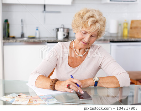 Woman counting her expenses using smartphone 104217905