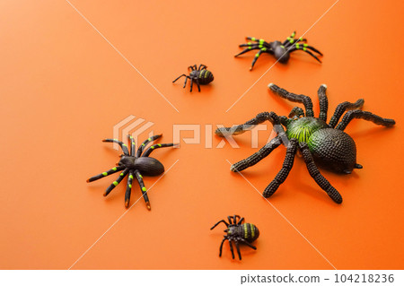 Group of black toy spiders on a orange background for halloween. 104218236