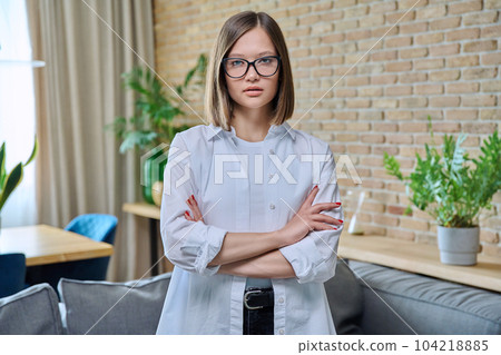 Portrait of young positive woman with arms crossed, in living room Portrait of young positive woman with arms crossed, in living room 104218885
