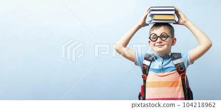 Funny school boy in glasses holding books on his head 104218962
