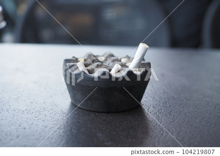 Close up burning cigarette in ashtray on table  104219807