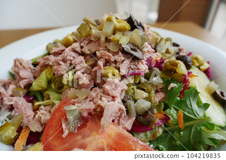 spoon pick tuna salad from a bowl on table  104219835