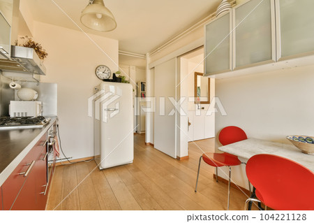 a kitchen with red chairs and a white refrigerator in the corner next to the counter top is a clock on the wall a kitchen with red chairs and a white refrigerator in the corner next to the counter top is a clock on the wall 104221128