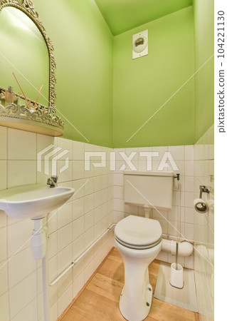 a small bathroom with green walls and white tiles on the wall, there is a mirror above the toilet bowl a small bathroom with green walls and white tiles on the wall, there is a mirror above the toilet bowl 104221130