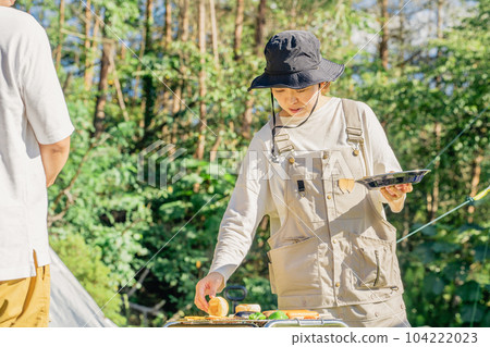 Family campers baking bread on camping barbecue 104222023