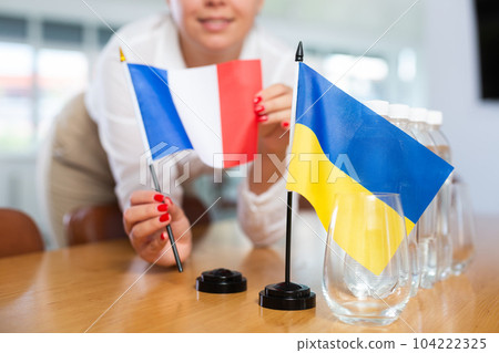 Female office coordinator setting flags of Ukraine and France on negotiating table Female office coordinator setting flags of Ukraine and France on negotiating table 104222325