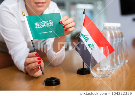 Preparing for business presentation - secretary places flags of Saudi Arabia and Iraq on negotiating table 104222339