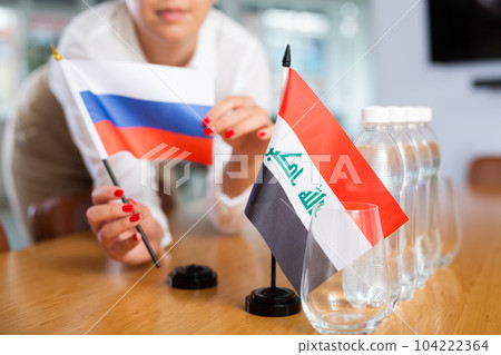 Unrecognizable girl sets midget flags of Iraq and Russia before international negotiations Unrecognizable girl sets midget flags of Iraq and Russia before international negotiations 104222364