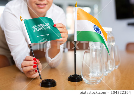 Unrecognizable girl sets midget flags of India and Saudi Arabia before international negotiations 104222394