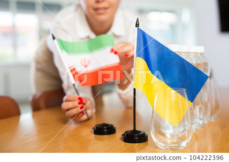 Unrecognizable girl sets midget flags of Ukraine and Iran before international negotiations 104222396