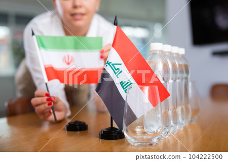 Unrecognizable girl sets midget flags of Iraq and Iran before international negotiations Unrecognizable girl sets midget flags of Iraq and Iran before international negotiations 104222500