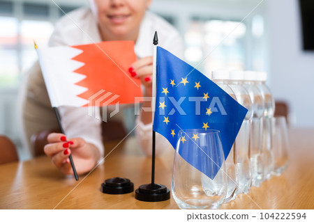 Female secretary places flags of Bahrain and European Union flag on the table before negotiations of top political figures Female secretary places flags of Bahrain and European Union flag on the table before negotiations of top political figures 104222594