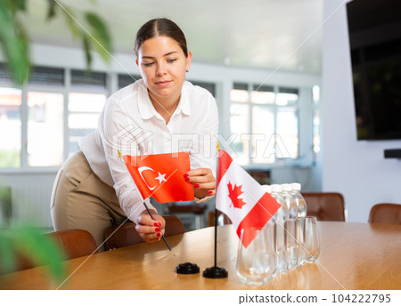 Young woman putting flags of Turkey and Canada on table in office Young woman putting flags of Turkey and Canada on table in office 104222795