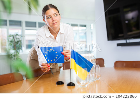 Young lady sets miniatures Ukrainian and European Union flags for international negotiations Young lady sets miniatures Ukrainian and European Union flags for international negotiations 104222860