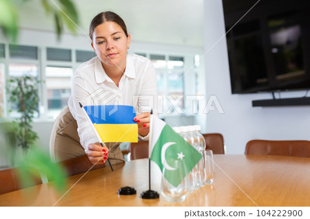 Young woman puts flags of Ukraine and Pakistan on table in office Young woman puts flags of Ukraine and Pakistan on table in office 104222900