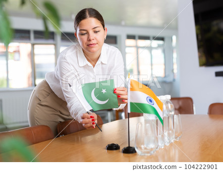Employee of delegation prepares negotiating table - sets up flag of India and Pakistan 104222901
