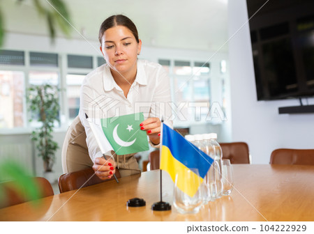 Young lady sets miniatures flags of Ukraine and Pakistan for international negotiations Young lady sets miniatures flags of Ukraine and Pakistan for international negotiations 104222929