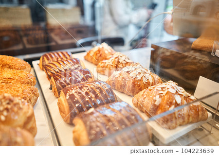 A variety of fresh pastries in the bakery window. almond croissant is fresh and hot in a cafe next to other types of pastries. The interior of an Italian restaurant. 104223639