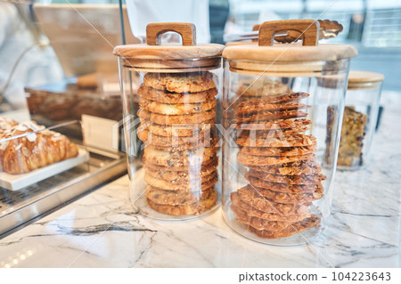 Oatmeal cookies on the marble kitchen table. Transparent glass jars with cookies in the interior of the cafe. Stylish interior of the kitchen of a trendy restaurant. decorative elements. 104223643