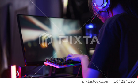 Female cyber hacker gamer pressing on keyboard to competition and playing games on computer 104224150