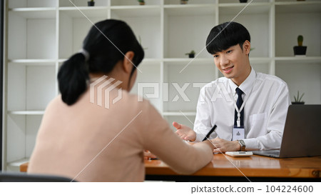 A professional Asian male banker meeting with a female client in the office. 104224600