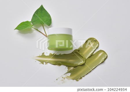 Unlabeled green jar decorated with fish mint leaves and smears of cream texture. Natural beauty blank label for branding mock-up concept Unlabeled green jar decorated with fish mint leaves and smears of cream texture. Natural beauty blank label for branding mock-up concept 104224934