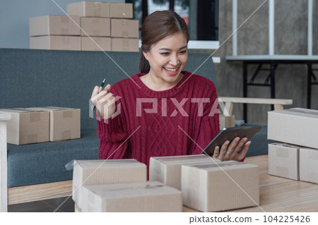 Happy young Asian woman entrepreneur, Smile for sales success after checking order from online shopping store in a tablet at home office, Concept of merchant business online and eCommerce Happy young Asian woman entrepreneur, Smile for sales success after checking order from online shopping store in a tablet at home office, Concept of merchant business online and eCommerce 104225426