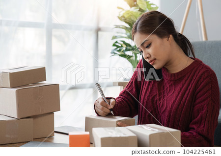 Cheerful small online business owner processing Internet store order for shipping, typing on laptop, speaking mobile phone, using gadgets for communication with clients Cheerful small online business owner processing Internet store order for shipping, typing on laptop, speaking mobile phone, using gadgets for communication with clients 104225461