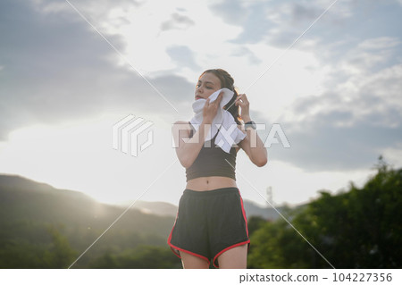 Wiping sweat after run Young athletic woman exercising in the city park outdoors 104227356