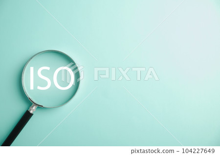 A magnifying glass is used to magnify the word ISO, highlighting its importance in standardization and security control. efforts of professionals in using technology and adhering to ISO 9001 standards 104227649