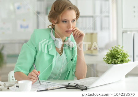Young businesswoman with headphones working 104228570