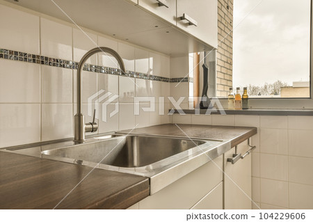 a kitchen with white tiles on the wall and wood countertop in front of the dishwasher's sink a kitchen with white tiles on the wall and wood countertop in front of the dishwasher's sink 104229606
