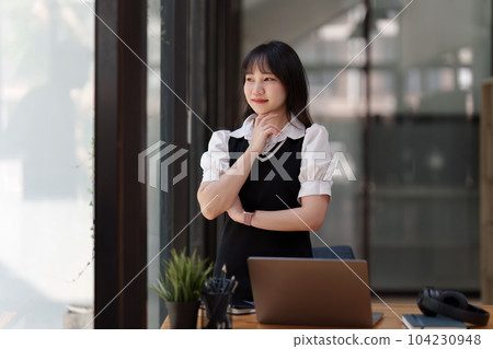 Online education, e-learning. Asian woman in stylish casual clothes, studying using a laptop, listening to online lecture, taking notes, online study at home Online education, e-learning. Asian woman in stylish casual clothes, studying using a laptop, listening to online lecture, taking notes, online study at home 104230948