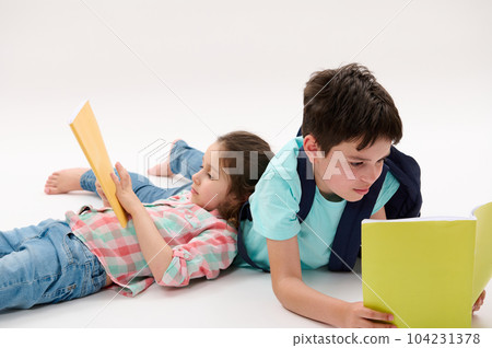 Two smart kids, lovely preschooler girl and teenage boy, brother and sister holding workbooks, doing homework while lying on a white background. Back to school concept. Children Childhood Education Two smart kids, lovely preschooler girl and teenage boy, brother and sister holding workbooks, doing homework while lying on a white background. Back to school concept. Children Childhood Education 104231378