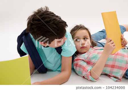 Authentic portrait of school kids, a little girl and teen boy looking at each other, holding textbooks and school supplies, isolated on white studio background. Back to school Education Study Learning Authentic portrait of school kids, a little girl and teen boy looking at each other, holding textbooks and school supplies, isolated on white studio background. Back to school Education Study Learning 104234000
