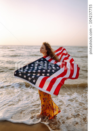 Young woman with american flag on the beach at sunset. 4th of July. Independence Day. Young woman with american flag on the beach at sunset. 4th of July. Independence Day. 104237755