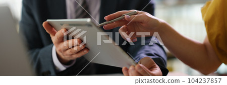 Business partners discussing information on tablet and showing screen with pen closeup 104237857