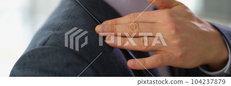 Businessman in business suit brushing off dust or dandruff from his shoulder closeup Businessman in business suit brushing off dust or dandruff from his shoulder closeup 104237879