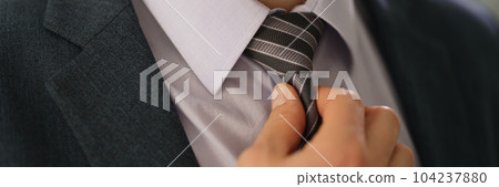 Elegant businessman in suit straightening tie on shirt closeup Elegant businessman in suit straightening tie on shirt closeup 104237880