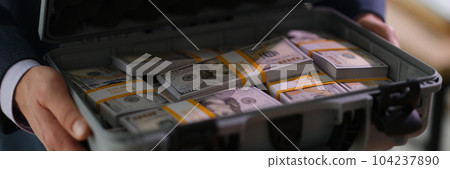 Banker holding suitcase with many dollar bills closeup Banker holding suitcase with many dollar bills closeup 104237890