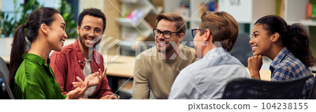 Creating success. Group of young happy multi racial business people communicating and sharing ideas while working together in the modern office Creating success. Group of young happy multi racial business people communicating and sharing ideas while working together in the modern office 104238155