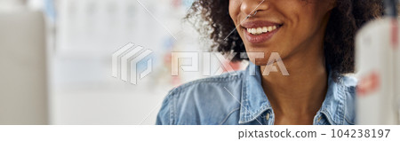 Professional African-American dressmaker works on modern laptop sitting at workplace 104238197