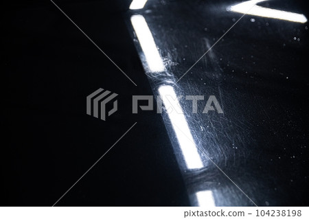 Before and after effect of a paint correction on the paintwork of a black car in a car detailing studio. 104238198